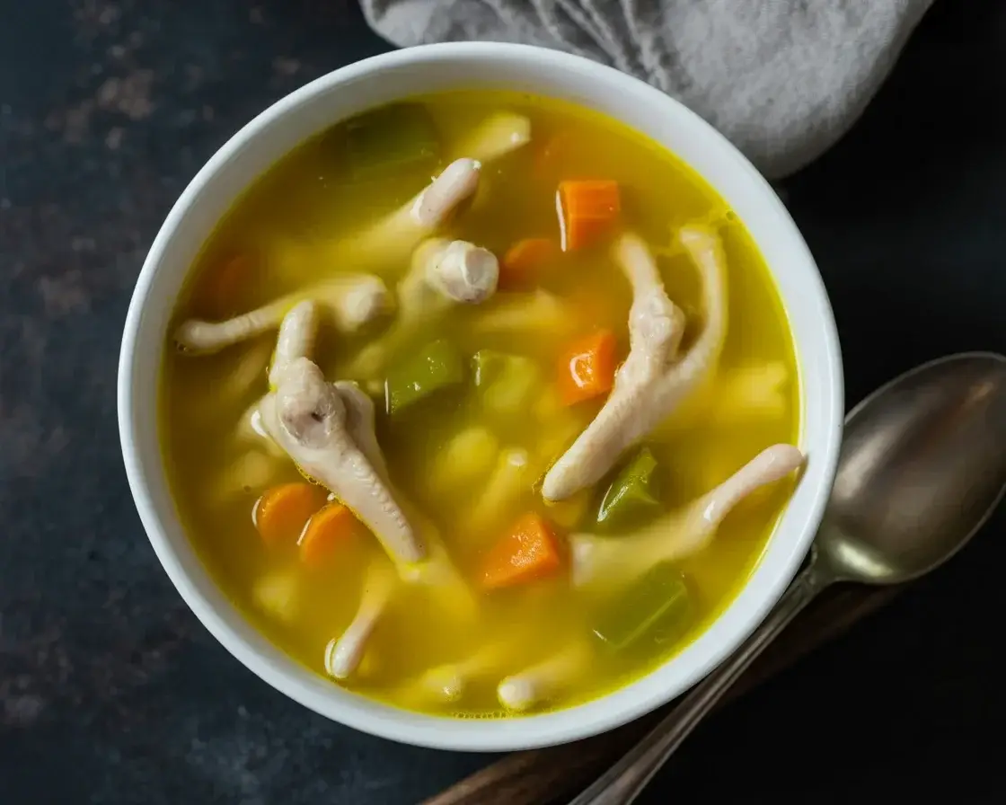 Bowl of chicken foot soup with vegetables and aromatic spices