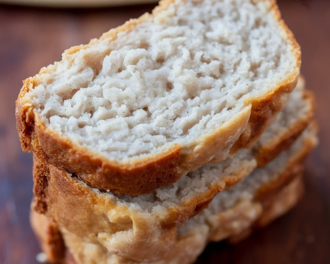 A slice of moist Almond Flour Banana Bread on a wooden table, garnished with banana slices.